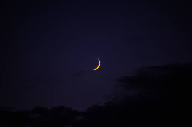 istock In the dark night sky, a beautiful yellow crescent moon shines bright 2184787824