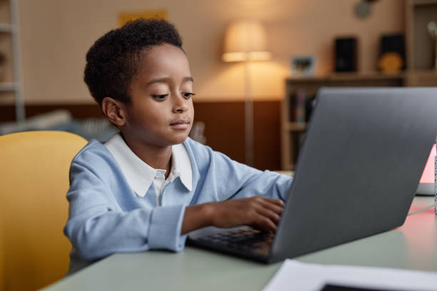 istock Concentrated Boy Writing on Laptop while Studying at Table in Kids Room 2184789238