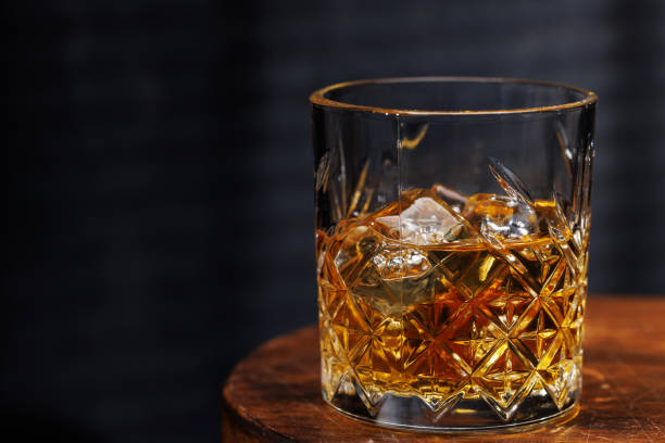 istock A whiskey glass resting on a wooden table, set against a dark background 2184790626