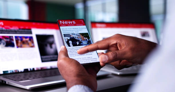 istock Watching Online News Article On Mobile Phone And Laptop 2184790871
