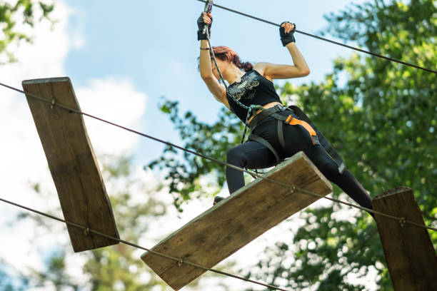 A Fearless Woman Skillfully Navigating a Challenging High Rope Course Above the Ground