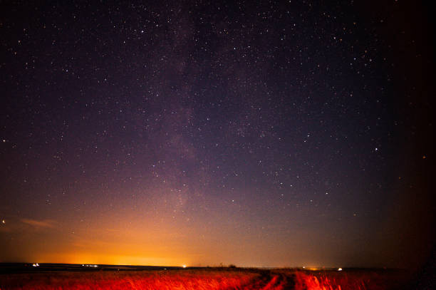 On a clear night, the breathtaking view of the Milky Way galaxy can be seen illuminating the night sky above a tranquil field