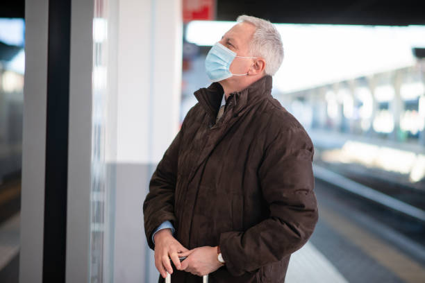 istock Businessman wearing protective face mask waiting for train in station 2184797342