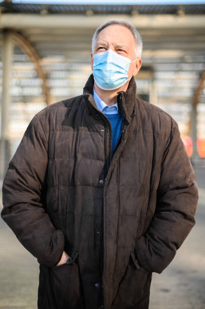 istock Senior businessman wearing protective face mask looking up at the sky 2184797449