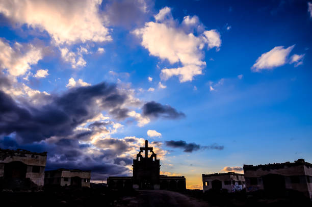 The sky is cloudy and the sun is setting. The sun is shining through the clouds, creating a beautiful and serene atmosphere