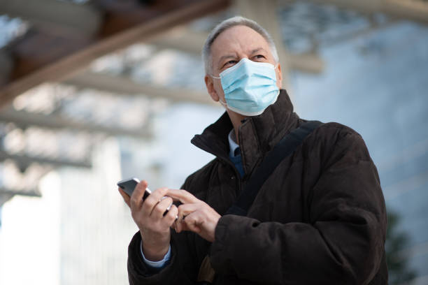 istock Mature businessman using a smartphone while wearing a protective face mask 2184800296