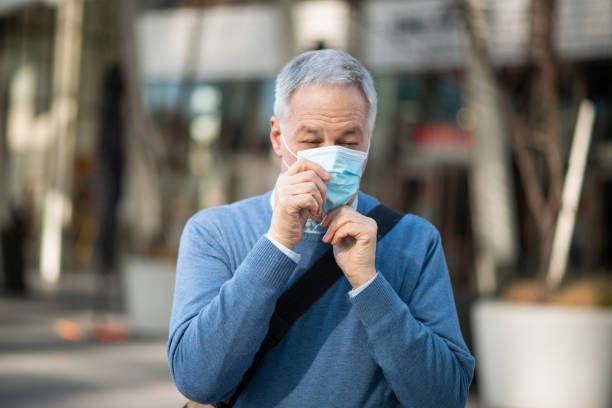 istock Senior man putting on protective face mask outdoors 2184800838