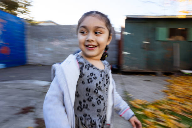 Happy hispanic girls (kindergarten aged) playing in their yard in the fall season. They are playing with toys and exploring their front and back yards as the leafs change colors.