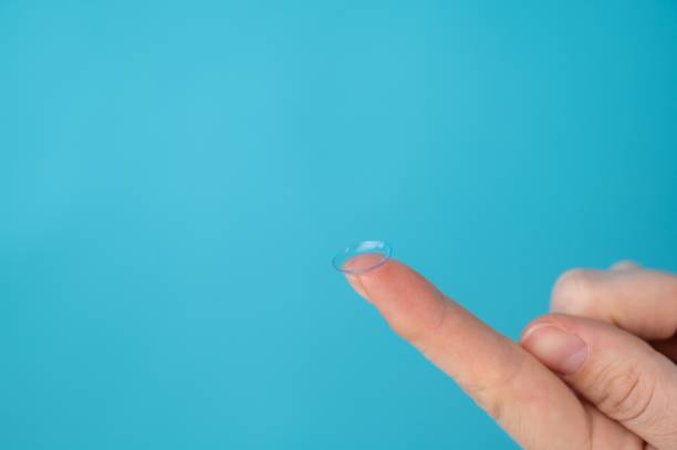 istock Woman holding contact lens on blue background. 2184807094