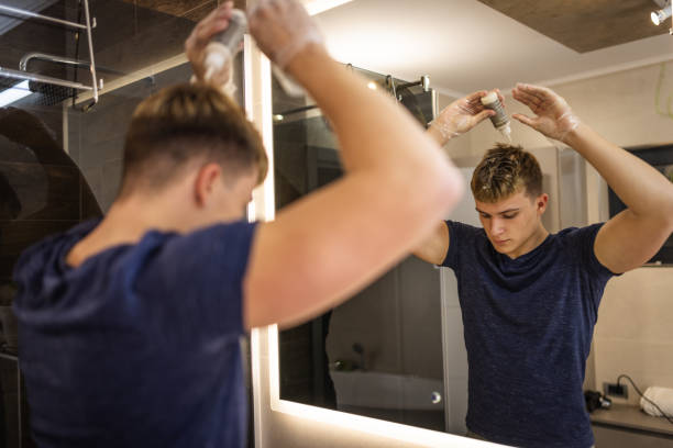 Young Man Applying Hair Dye in Modern Bathroom Mirror