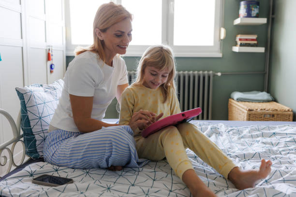 istock Mother and daughter embracing and using a tablet in bed 2184815161