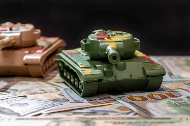 istock Toy tanks against a background of unfolded dollar notes and a black background, 2184815301