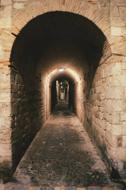 istock Illuminated medieval archway leading to a narrow alley 2184817699