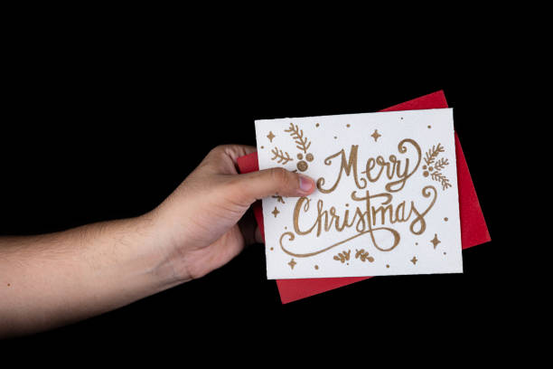 istock Hand Holding Decorative Merry Christmas Card on Black Background 2184817943