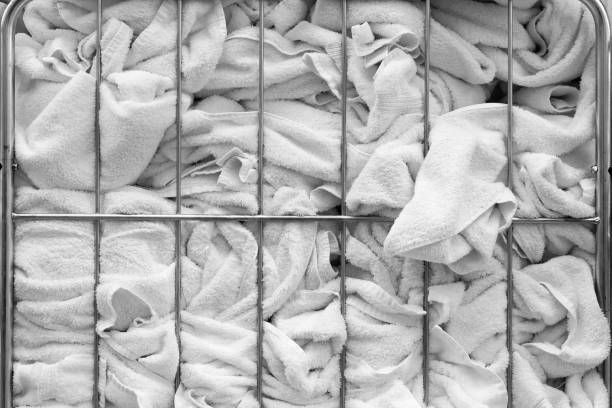 A stack of white towels in a metal basket in a laundry. A close-up of crumpled white towels.