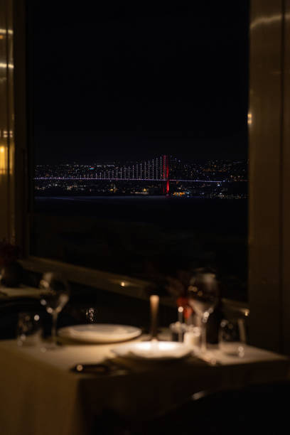 Night view of Istanbul Bosphorus Bridge seen from a luxurious restaurant with moonlit sky, Turkey