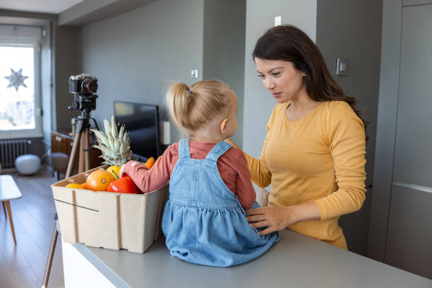 istock Mother and toddler filming social media content in modern kitchen setting 2184826567