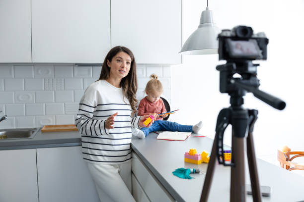 istock Mother recording vlog with baby in kitchen setting 2184826601