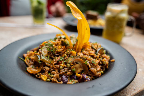 A vegan risotto with roasted pumpkin, mushrooms, and fresh spinach served in a white bowl on a light background, top view, closeup view