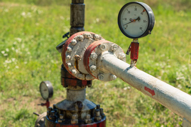 Pressure gauges on pipes through which oil is pumped. There is rust and traces of oil products on the pipes. Dirty extraction of black gold from the well. Pollution of the environment