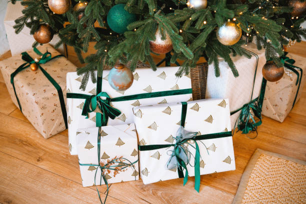 istock Wrapped Christmas presents under a decorated tree in a cozy living room 2184840601