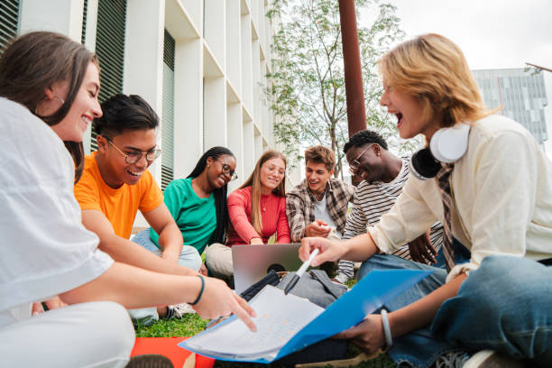 istock Group of multiracial students doing homework together, sitting on the university campus lawn. Teenagers sharing notes to study for their high school exam. Young people talking and learning the lesson 2184849121