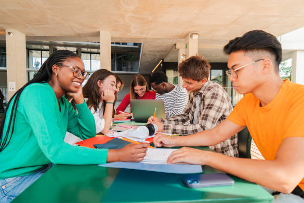 istock Happy multiracial group of high school students working together, sitting at library with notebooks, writing and using a laptop to search information. Young teenagers studying exams at university 2184849449