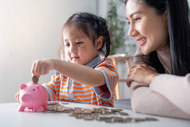 istock Young Learner Collecting Coins with Encouraging Parent 2184851144