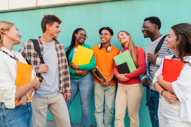 istock Diverse group of students talking and smiling outdoors, young friends holding notebooks and backpacks, socializing and enjoying conversation, happy multicultural college group standing at university 2184852103