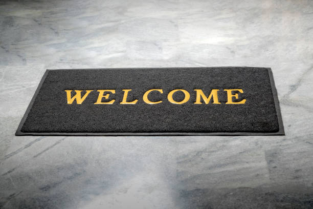 istock Black door mat with welcome text on it with floor background 2184852631