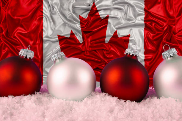 Four Christmas ornaments arranged in a row, placed on a bed of artificial snow. Canadian flag in the background, creating a festive atmosphere.