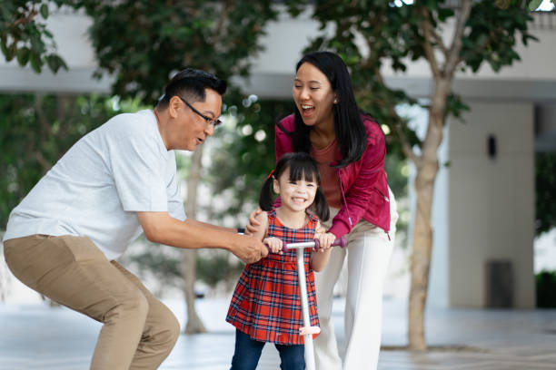 istock Young girl playing push scooter with her parents 2184853732