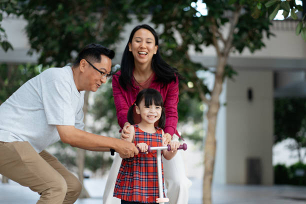 istock Young girl playing push scooter with her parents 2184853741