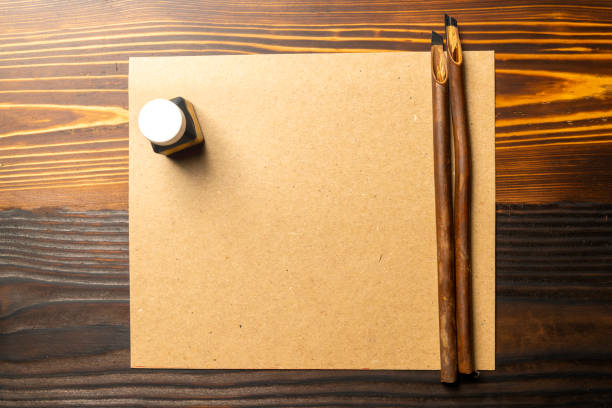 istock Two calligraphy reeds covered ink with inkwell and empty brown card on the table 2184855344