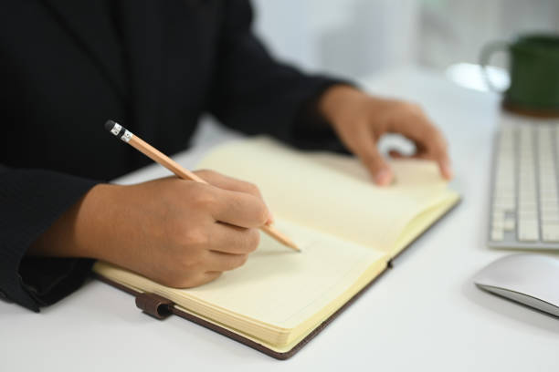 istock Unrecognizable businesswoman writing in a journal to remember a task at desk 2184864957