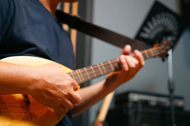 Close up of Man hand playing Thai Mandolin, Phin and practicing in home studio
