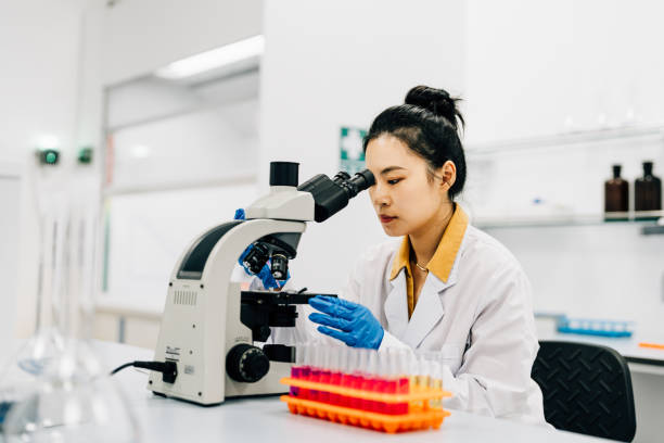 istock Asian female scientist looking trough the microscope in lab. 2184874810