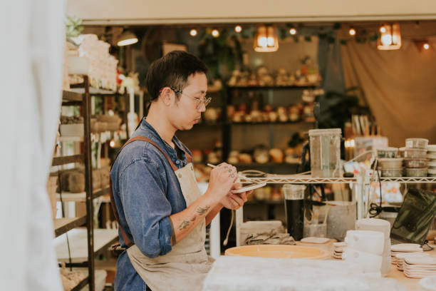 istock Craftsman while Painting dish while working at small business. 2184883458