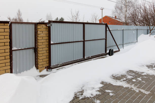 istock A gate is covered in snow and is attached to a brick wall 2184884022