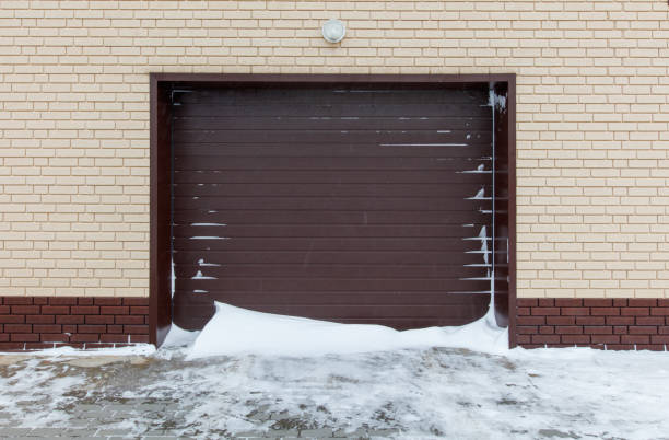 A garage door is open and snow is piled up against it