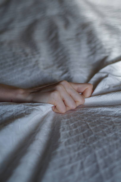 istock Woman hand clutches or grasps white sheets - orgasm, pleasure concept 2184885565