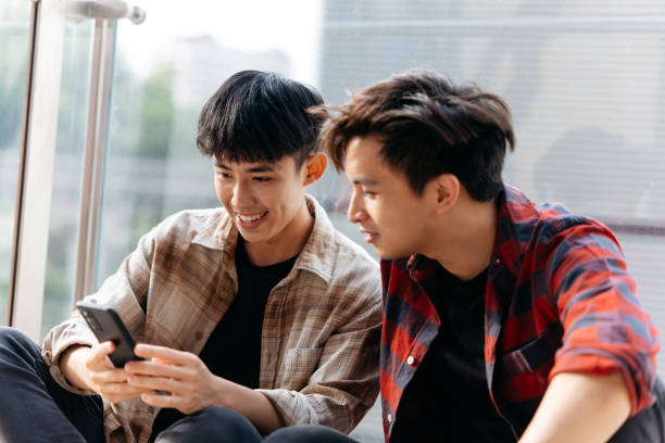 istock Two Asian Chinese men sitting and using phone in the city. 2184888918