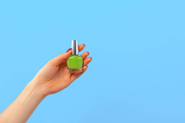 istock Female hand holding nail polish against blue background 2184889687