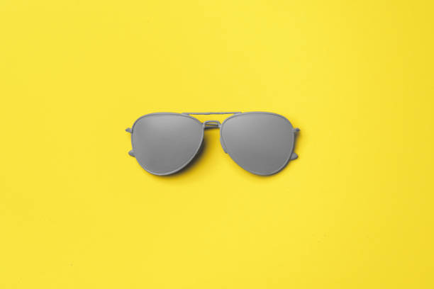 istock Gray painted sunglasses on yellow background top view 2184890347