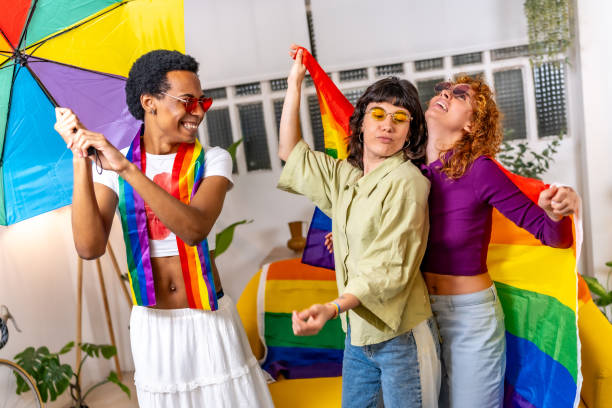Friends having fun dancing and celebrating pride at home Friends having fun using rainbow umbrella and lgbt flag dancing and celebrating pride at home gay man men sunglasses party stock pictures, royalty-free photos & images