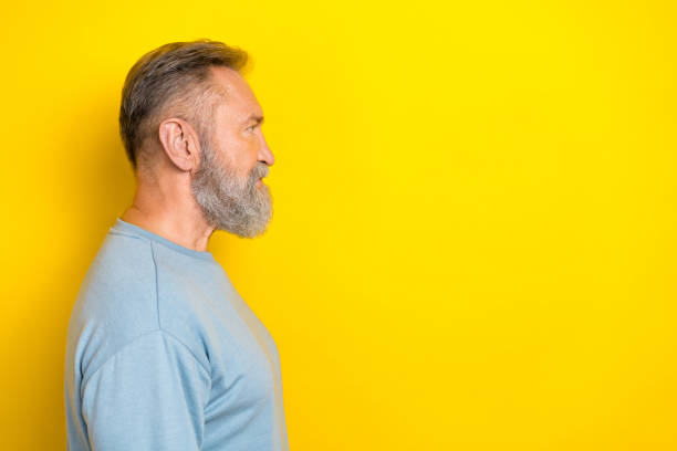 istock Photo of cheerful handsome man pensioner dressed blue pullover looking empty space isolated yellow color background 2184894237