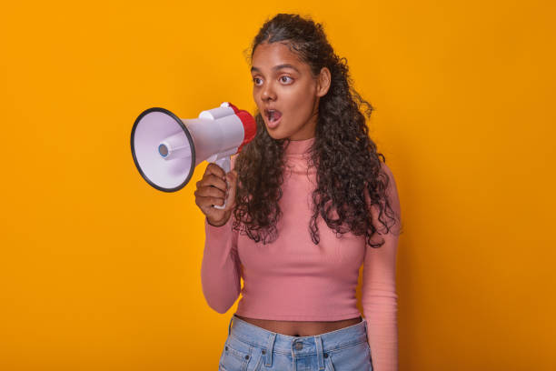 istock Young Woman Passionately Speaking With a Megaphone Against a Vibrant Backdrop 2184897577