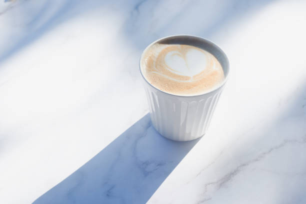 istock hot latte coffee in white ceramic coffee cup on white marble table. 2184897906