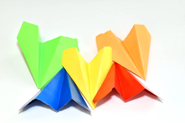 Paper airplanes of different colors lie next to each other on a white background.