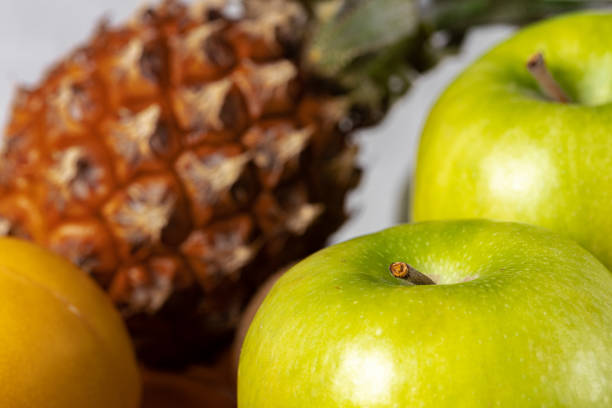 Pineapple, green apples and apricot on table, close up